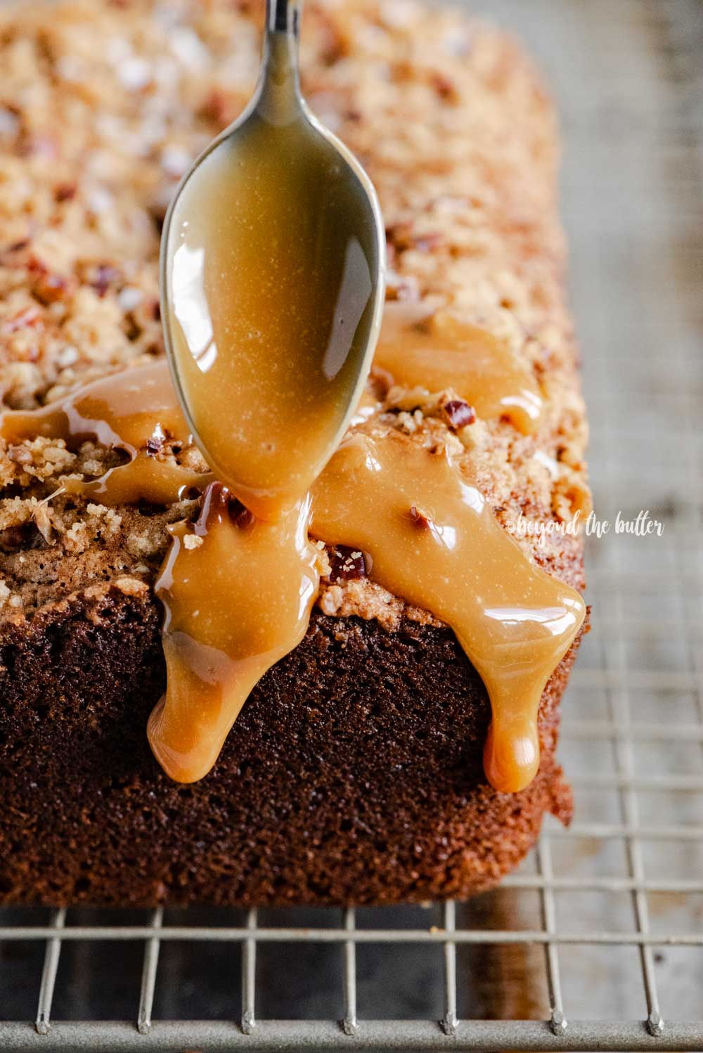 Angled image of salted caramel banana nut bread loaves on a wire cooling rack with caramel drizzled over the top | All Images © Beyond the Butter™