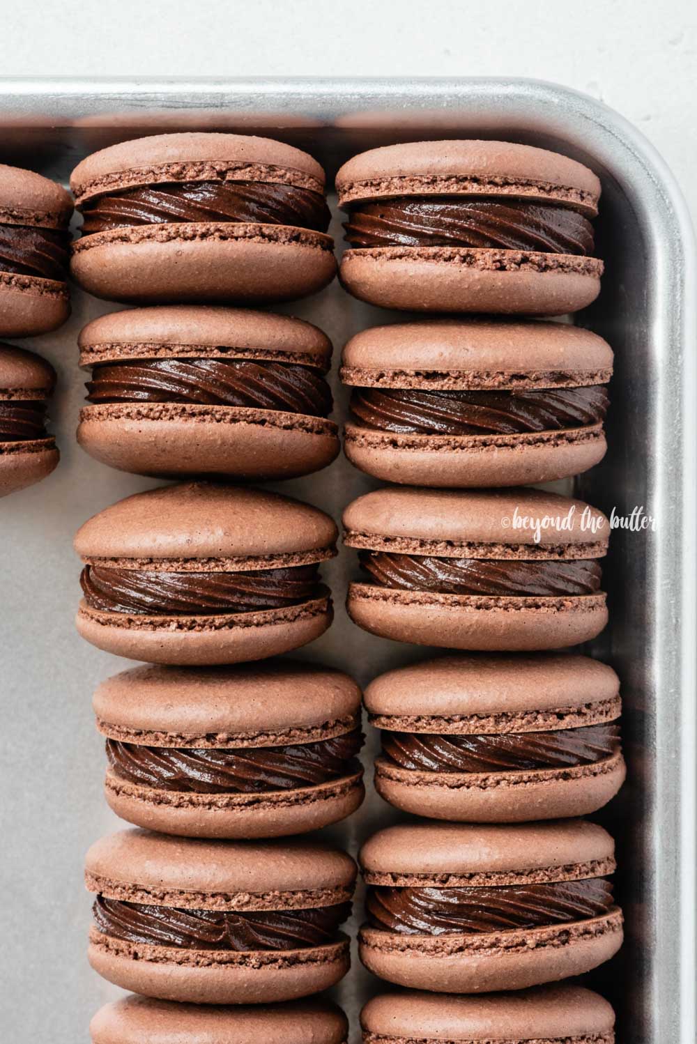 Small baking tray lined with dark chocolate macarons | All Images © Beyond the Butter™