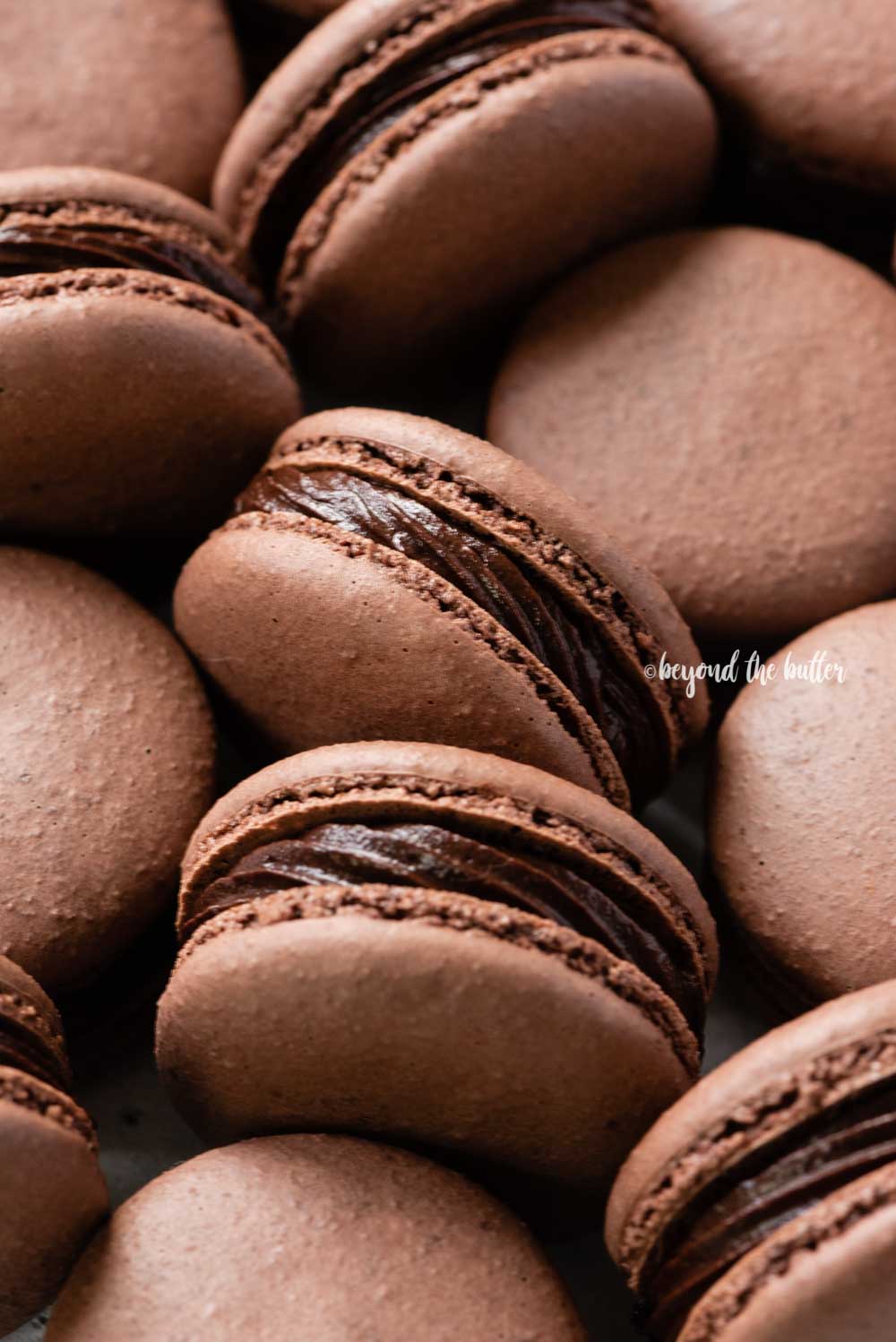 Angled image of randomly placed dark chocolate macarons | All Images © Beyond the Butter™