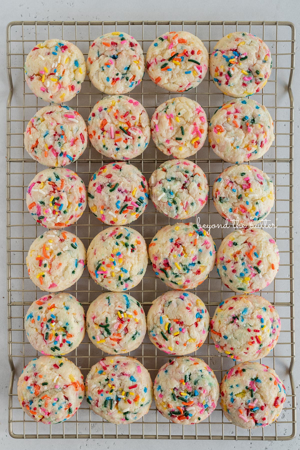 Funfetti gooey butter cookies lined up in rows on a wire cooling rack.