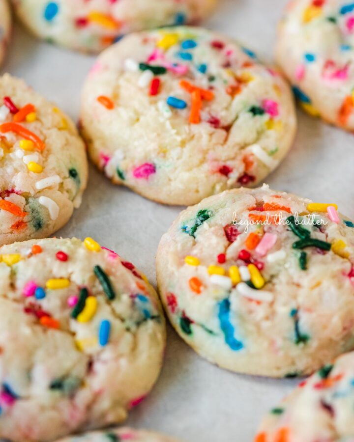 Funfetti butter cookies lined up on white parchment paper.