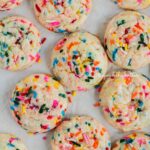 Funfetti butter cookies on white parchment paper-lined baking sheet.