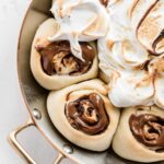 Overhead closeup image of s'mores rolls partially covered with marshmallow topping.