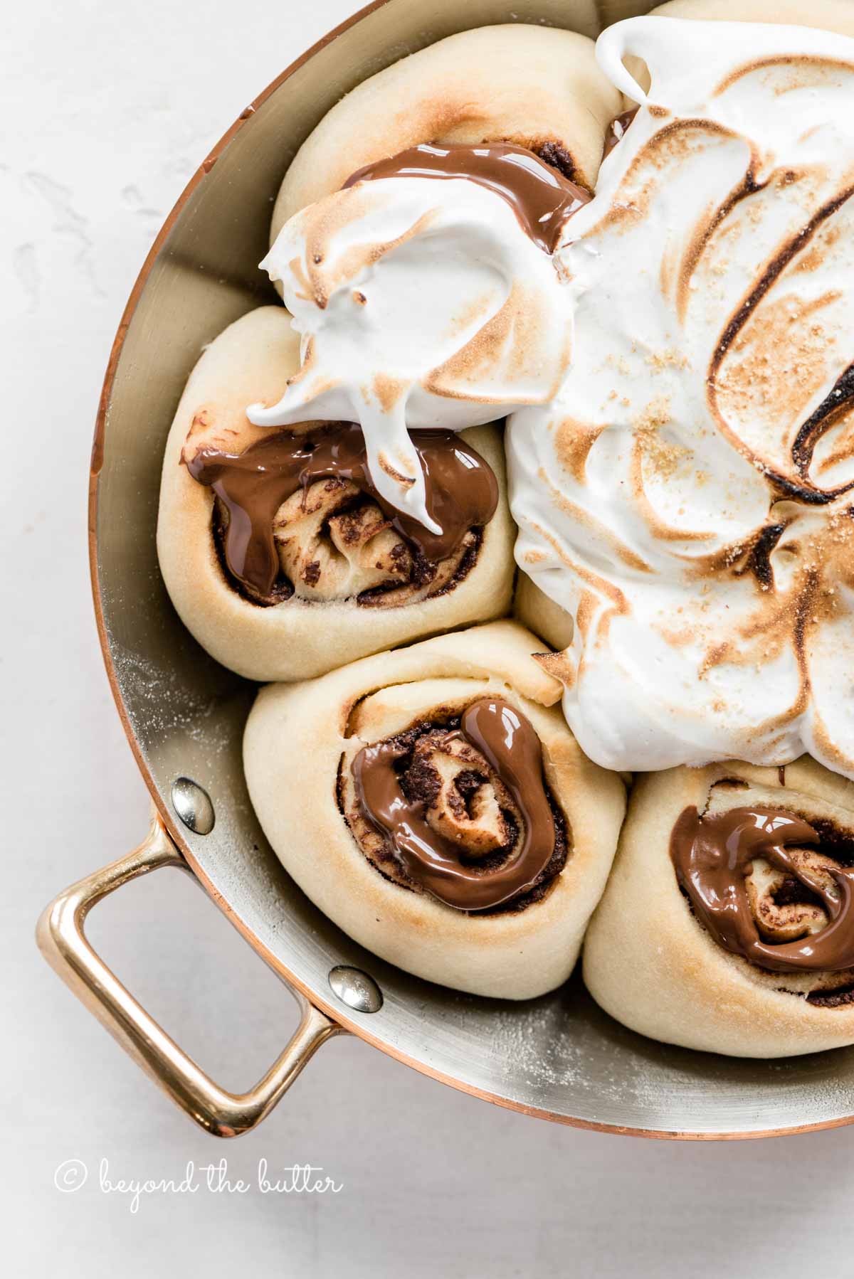 Overhead closeup image of s'mores rolls partially covered with marshmallow topping.