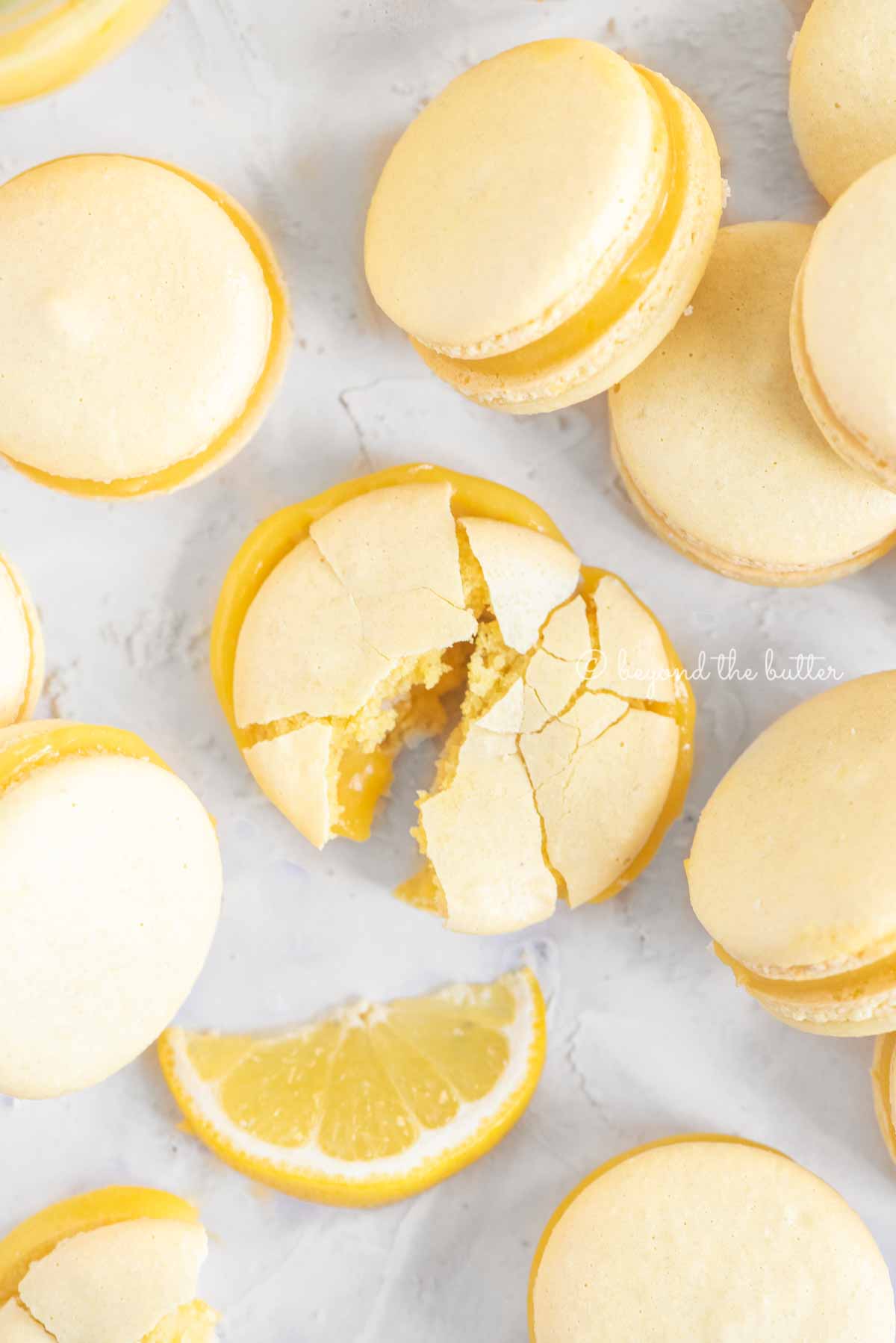 Overhead image randomly placed lemon macarons with the center macaron broken apart | All Images © Beyond the Butter™
