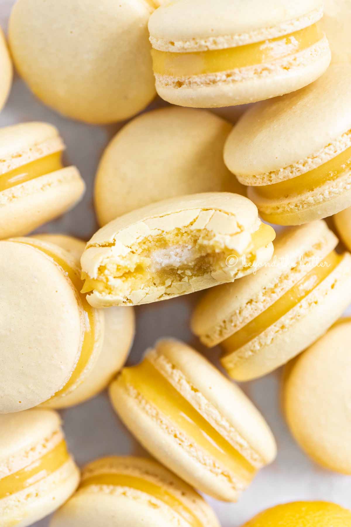 Randomly placed lemon macarons with a bite taken out of the center macaron | All Images © Beyond the Butter™