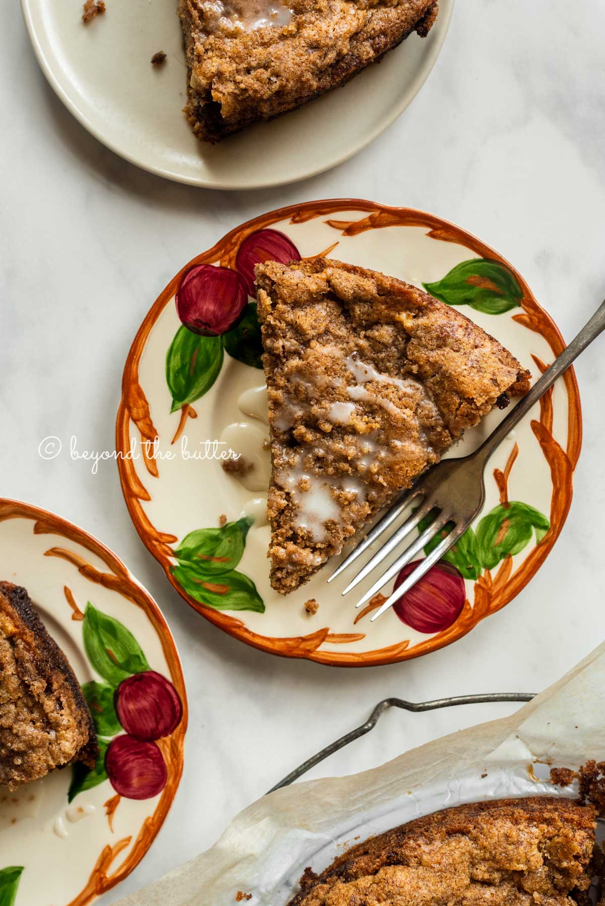 Slices of warm apple coffee cake on dessert plates drizzled with a simple vanilla glaze | All Images © Beyond the Butter™