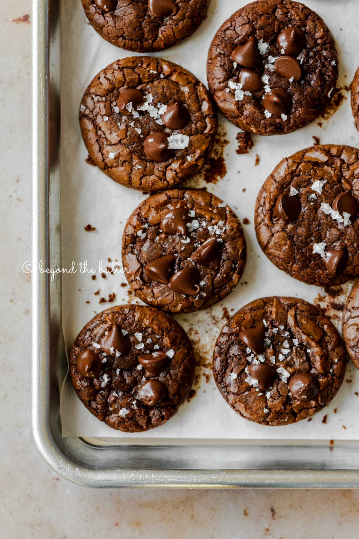 Salted brownie crinkle cookies on a parchment lined baking sheet | All Images © Beyond the Butter®