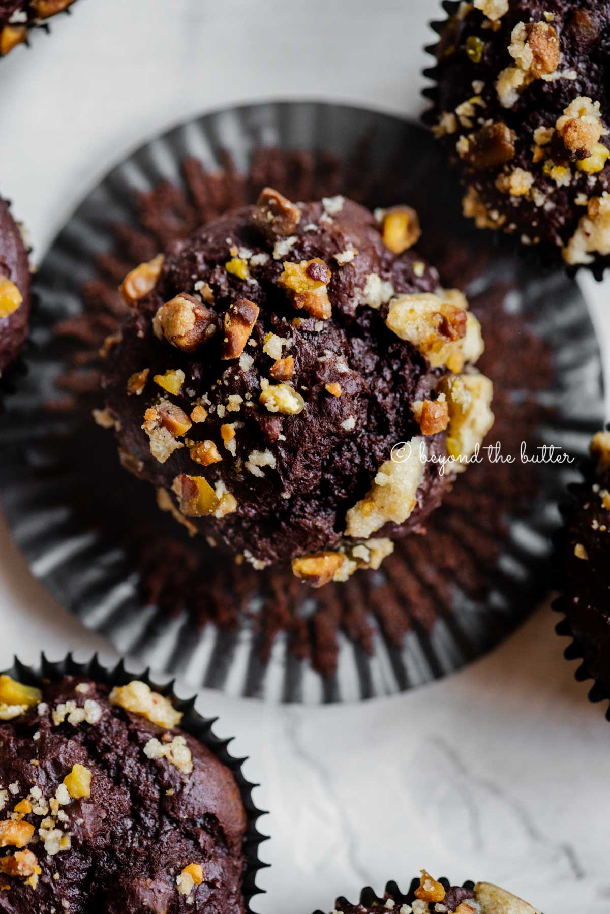 Dark chocolate pistachio cream cheese muffins with center muffin unwrapped | All Images © Beyond the Butter™