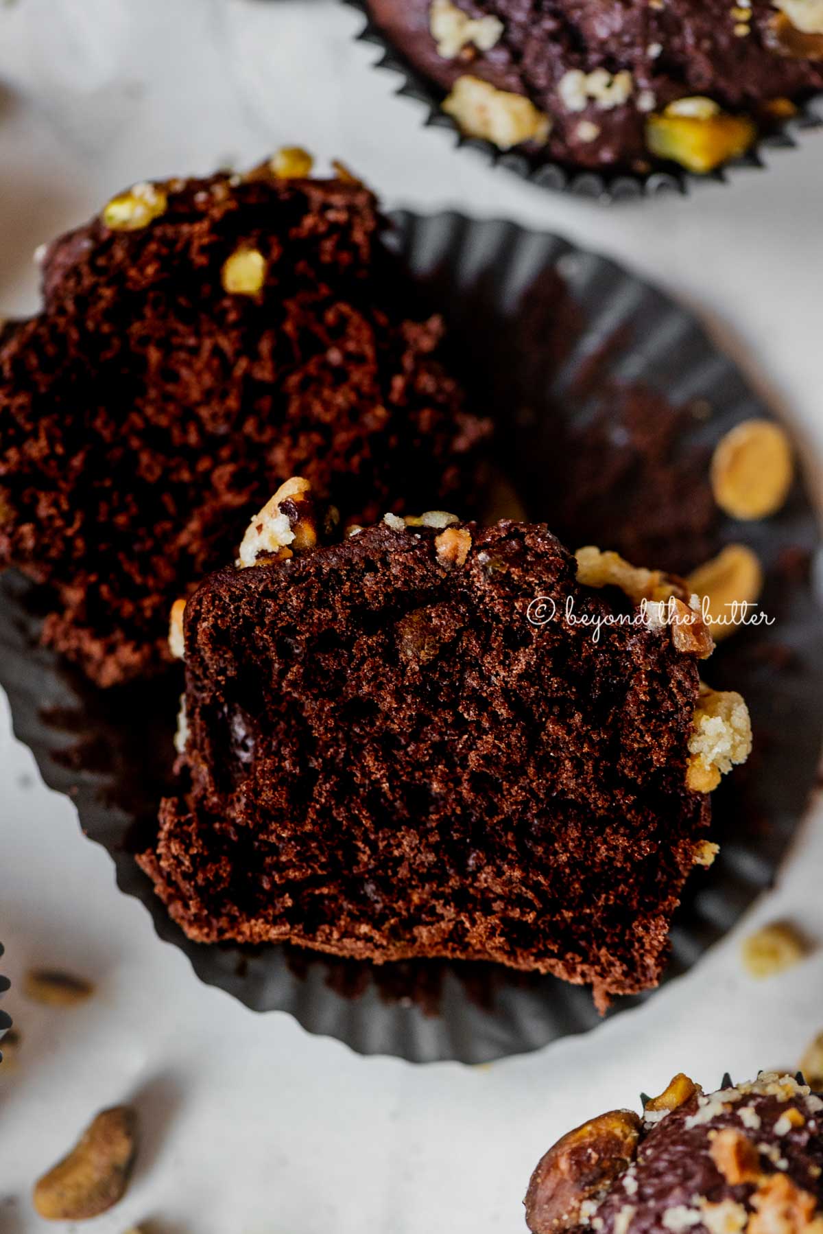 Dark chocolate pistachio cream cheese muffins with center muffin unwrapped and cut in half | All Images © Beyond the Butter™