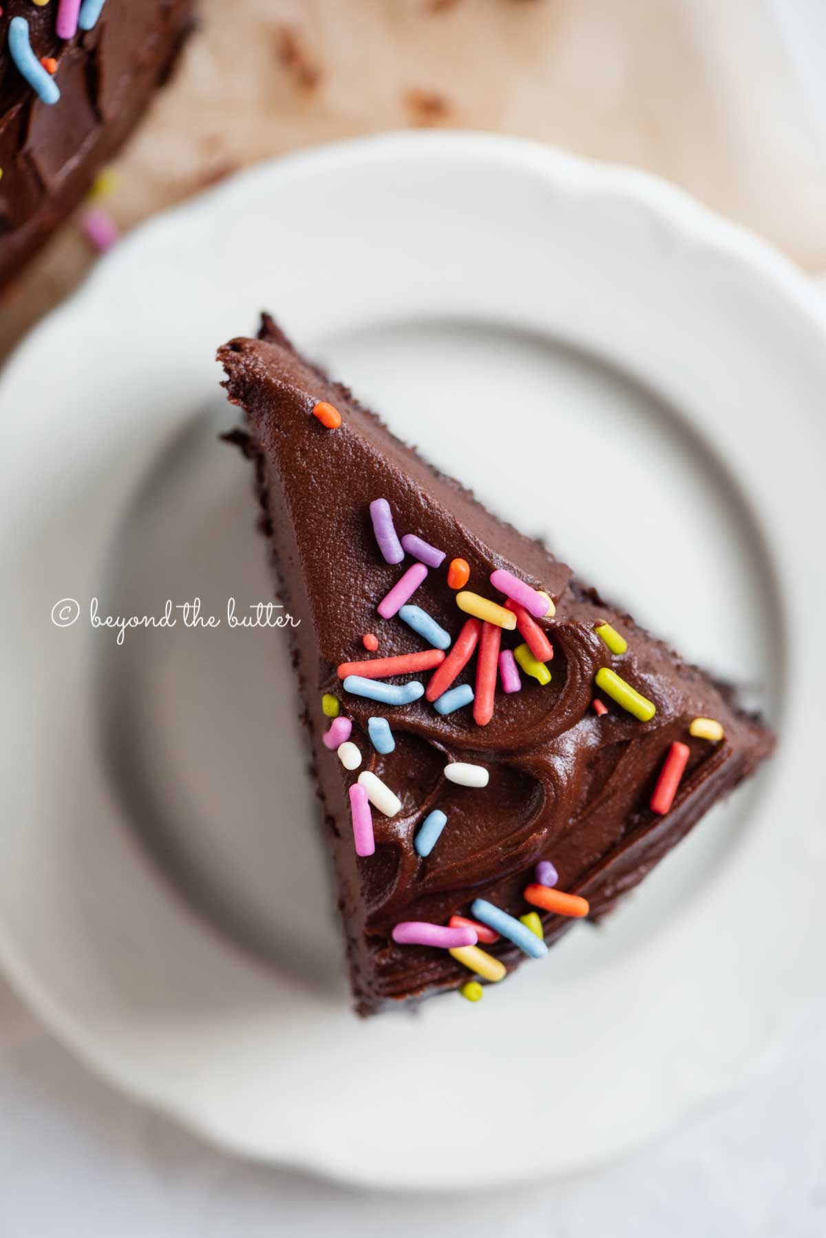 Overhead closeup image of single slice of 6 inch chocolate cake on white dessert plate | All Images © Beyond the Butter®