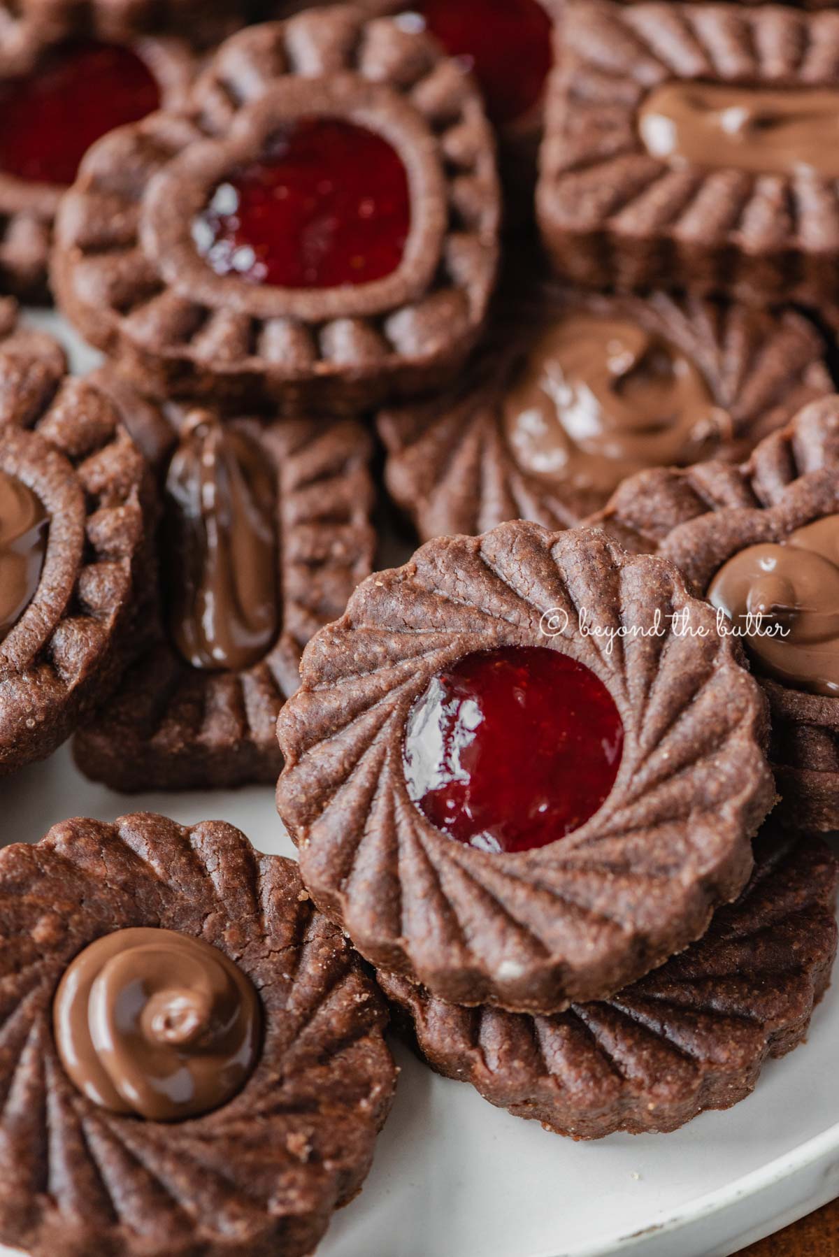 Closeup image of chocolate thumbprint cookies on white dessert plate.