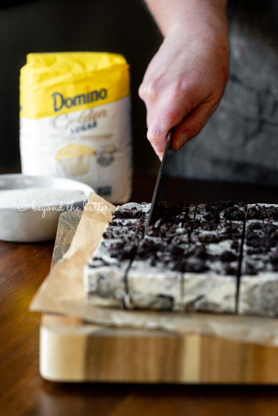 Cutting the cookies and cream fudge with small bag of Domino® Golden Sugar in the background | All Images © Beyond the Butter®