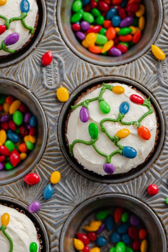 Cupcake tin with decorated small batch gingerbread cupcakes with marshmallow frosting and rainbow chocolate covered sunflower seeds | All Images © Beyond the Butter®