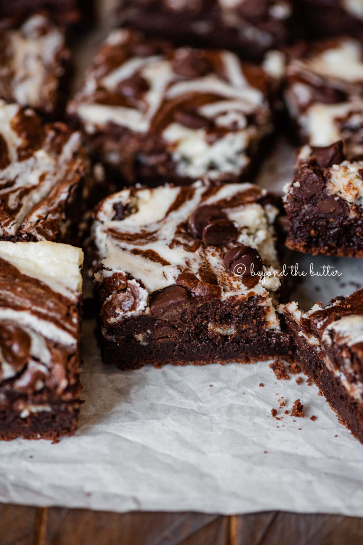 Chocolate chip cream cheese brownies on parchment paper | All Images © Beyond the Butter®
