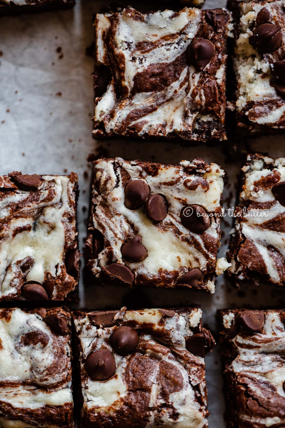 Chocolate chip cream cheese brownies on parchment paper.