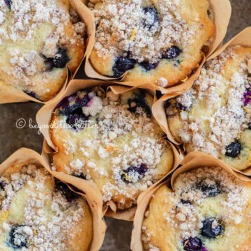 Baking tray filled with bakery style lemon blueberry muffins garnished with slices of lemons and blueberries | All images © Beyond the Butter®