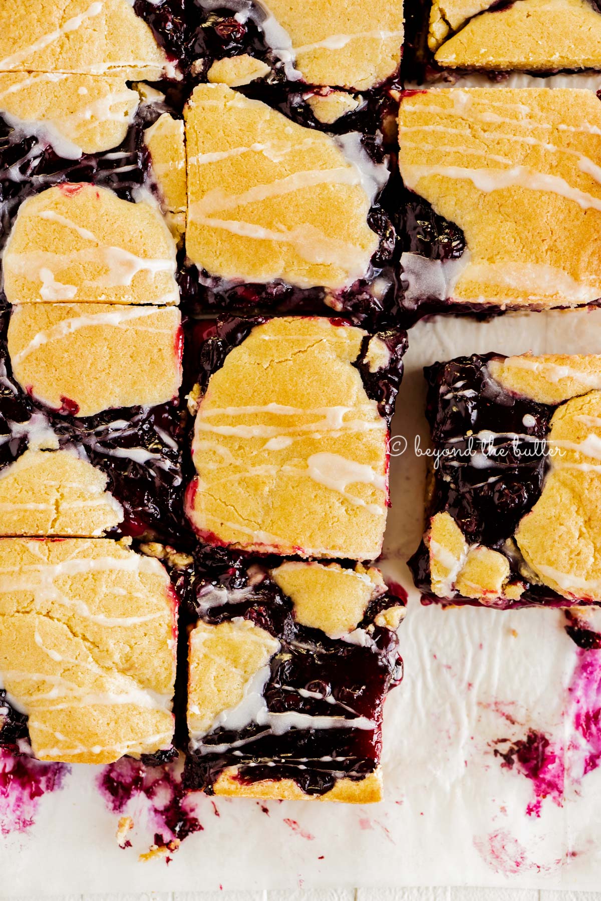 Blueberry swirl coffee cake squares on a white parchment paper background | All Images © Beyond the Butter®