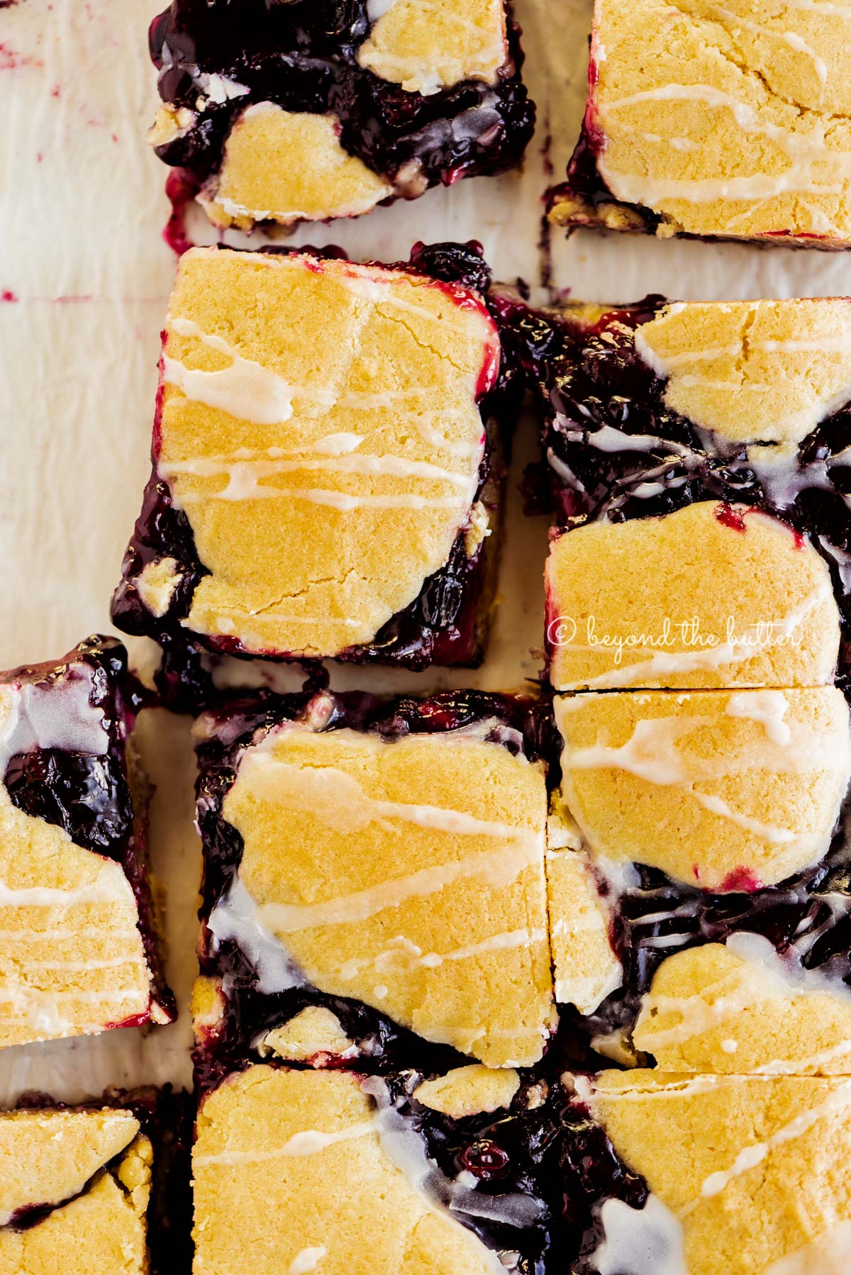 Blueberry swirl coffee cake squares on a white parchment paper background | All Images © Beyond the Butter®