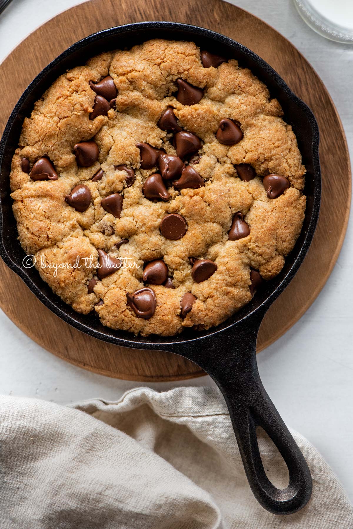 Just baked chocolate chip skillet cookies on light gray background with cloth napkin | All Images © Beyond the Butter®