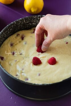 Topping the lemon raspberry ricotta cake with fresh raspberries before baking | © Beyond the Butter®