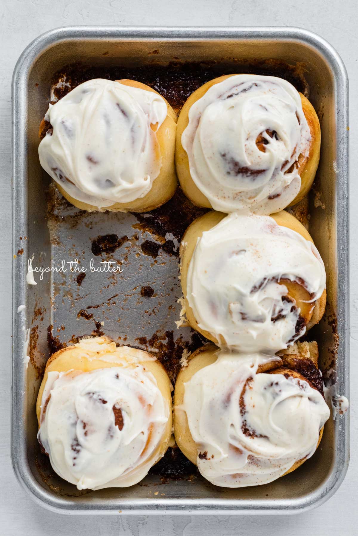 Just frosted small batch cinnamon rolls with one already eaten from BeyondtheButter.com | © Beyond the Butter®