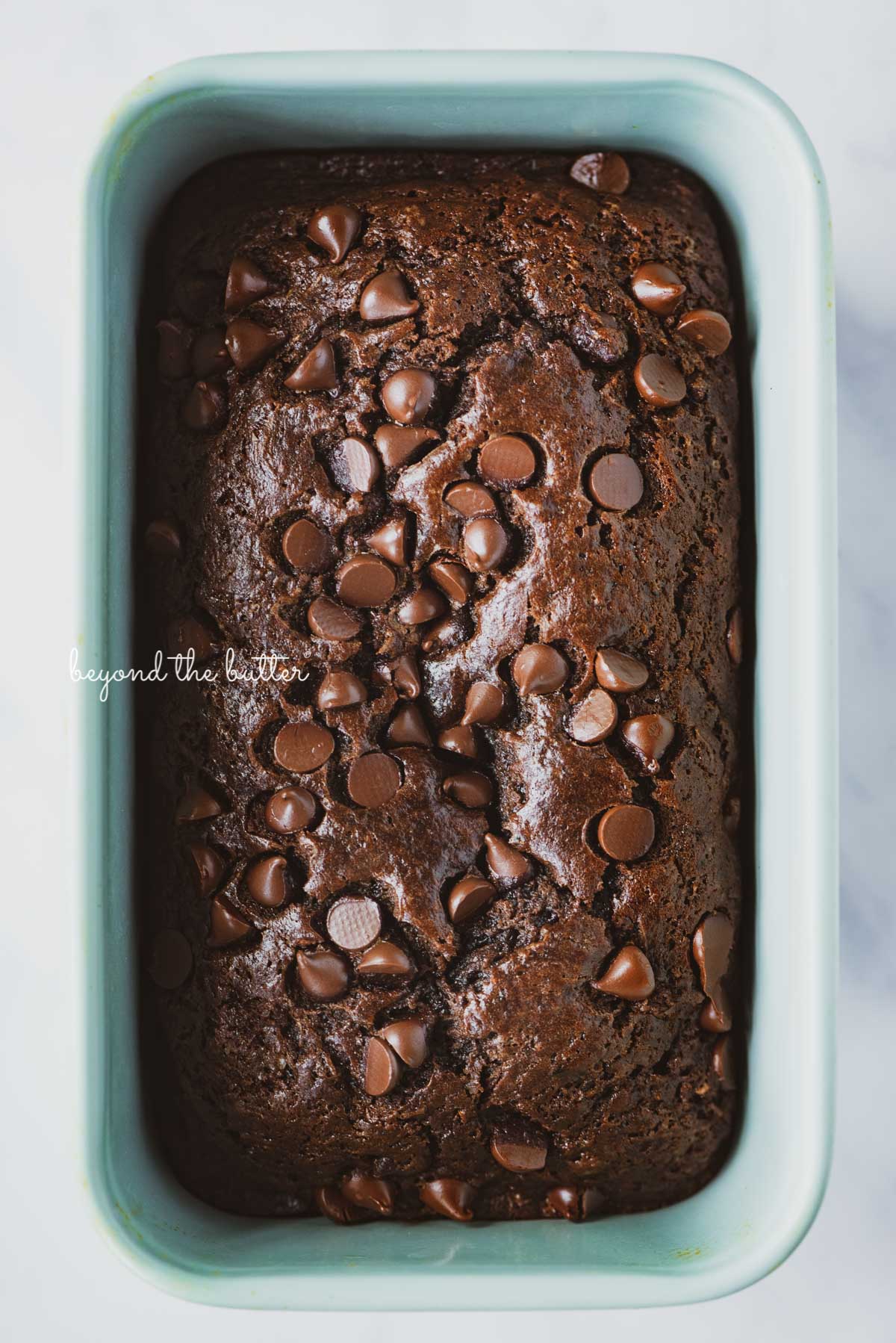 Freshly baked one bowl chocolate zucchini bread in a blue loaf tin | © Beyond the Butter®