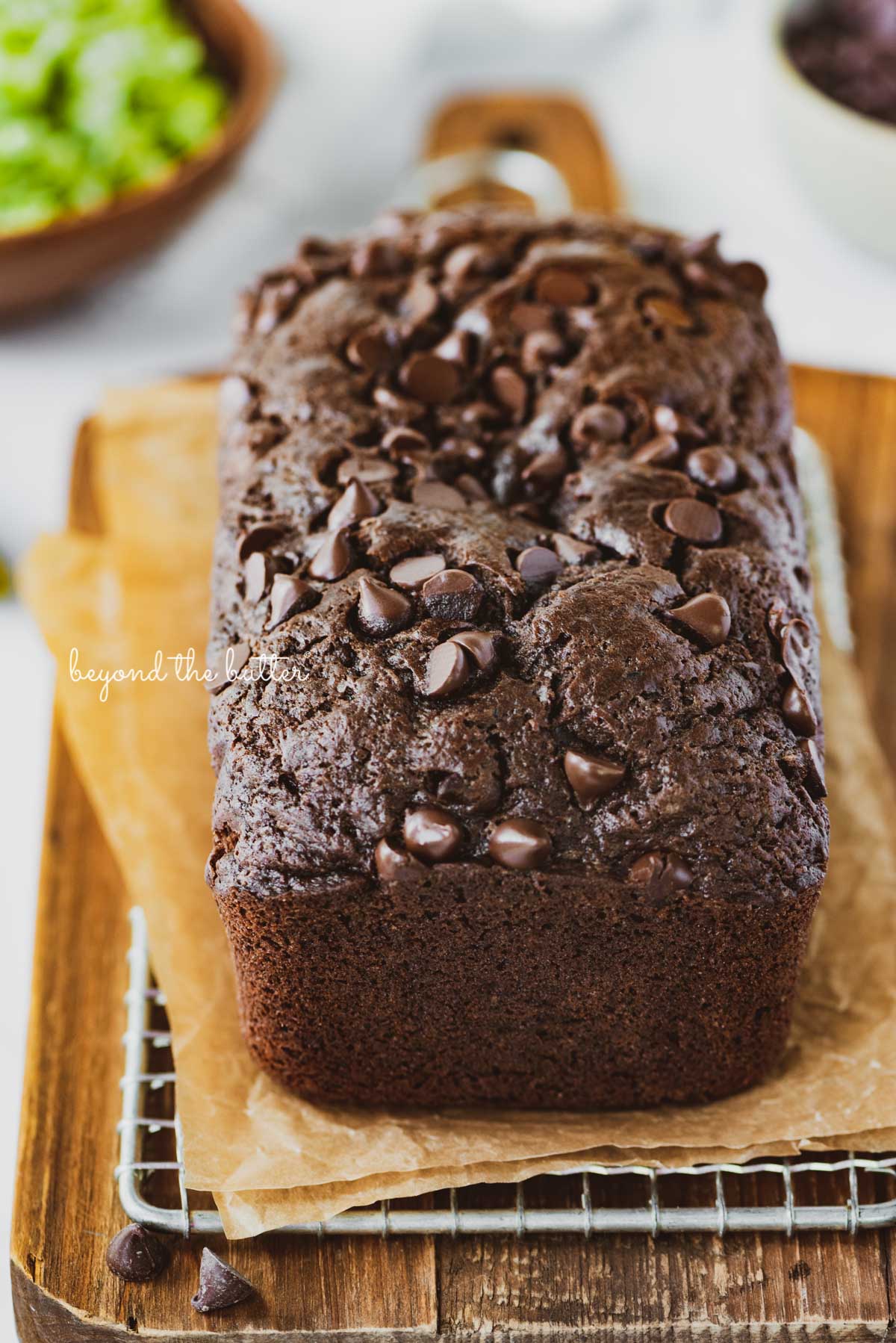 Sliced chocolate zucchini bread on a cutting board with a knife | © Beyond the Butter®
