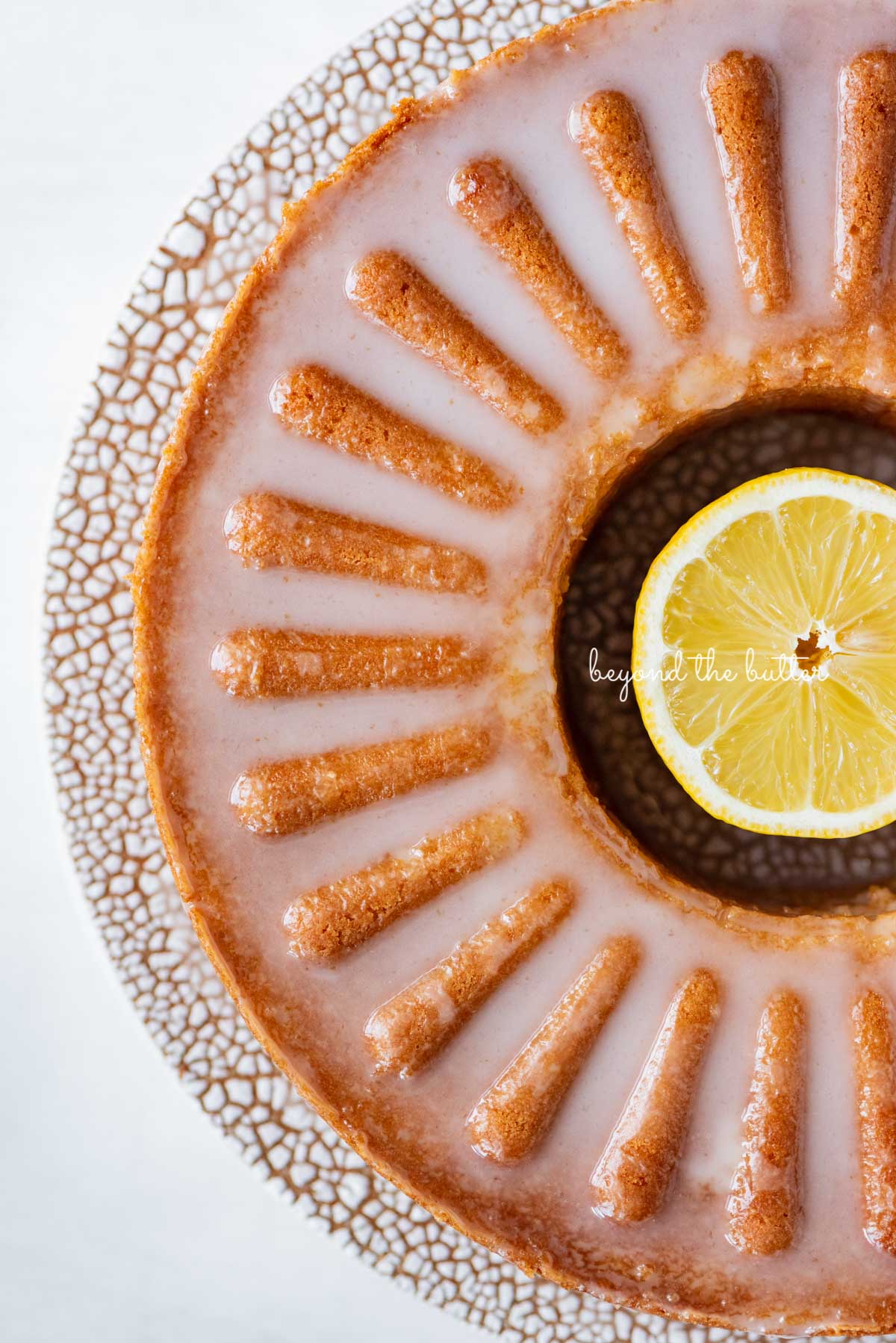 Glazed lemon cream cheese pound cake on a ceramic cake stand from Sweetheart Ceramics | © Beyond the Butter®