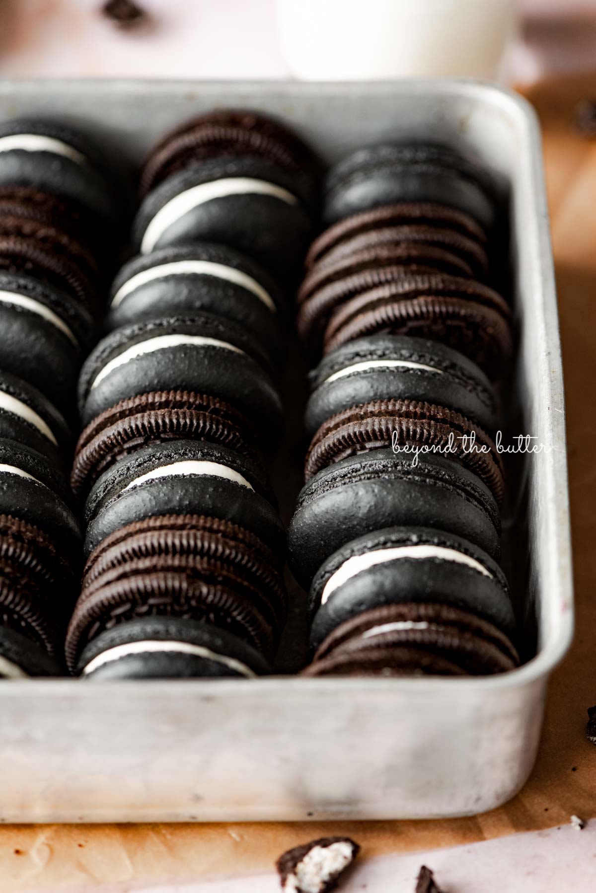Oreo macarons and oreo cookies in a vintage baking tin on parchment paper | © Beyond the Butter®