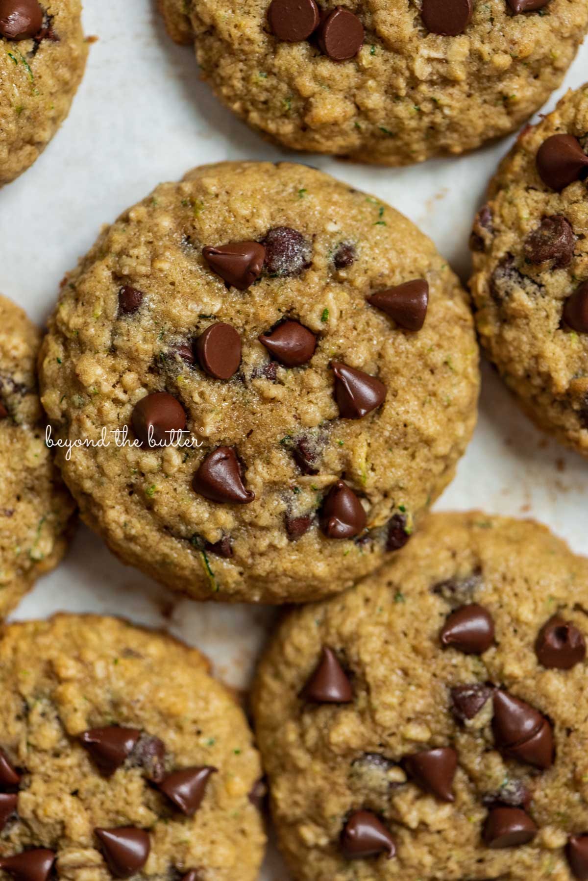 Zucchini chocolate chip oatmeal cookies on a parchment paper lined baking sheet.