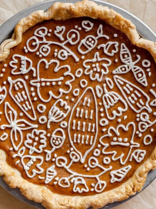 Pumpkin pie with decorative cream cheese frosting design.