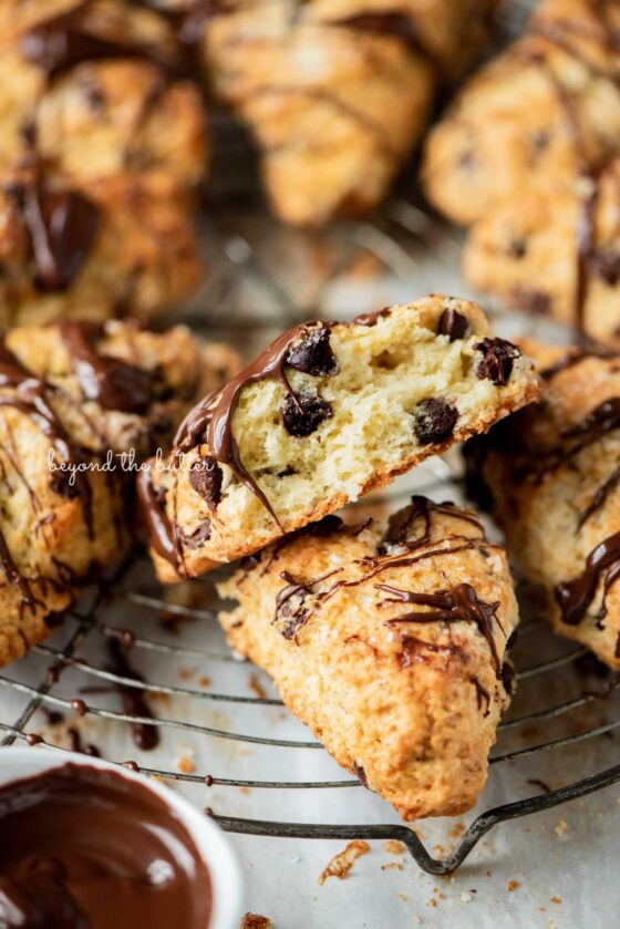 Cut view of chocolate chip scone drizzled in melted dark chocolate on a wire cooling rack | © Beyond the Butter®