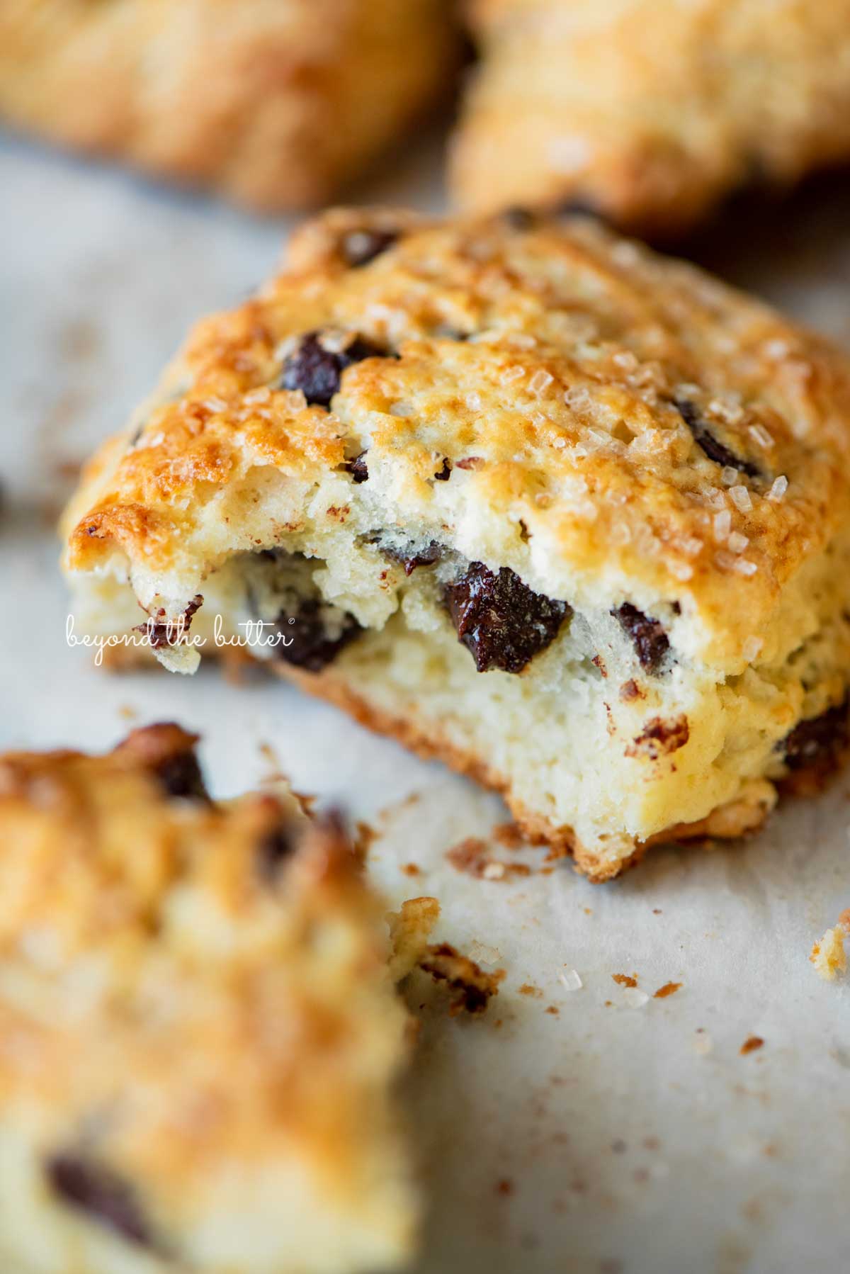 Halved chocolate chip scone on parchment paper lined baking sheet | © Beyond the Butter®