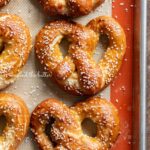 Homemade soft pretzels on a silicone baking mat and baking sheet.