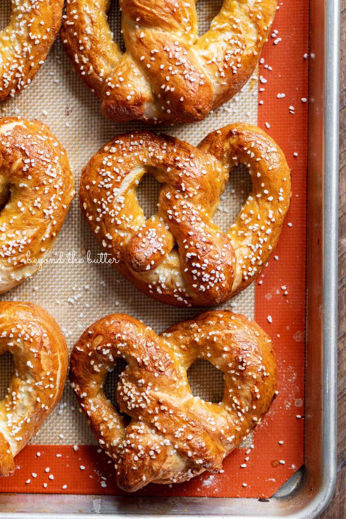 Homemade soft pretzels on a silicone baking mat and baking sheet.
