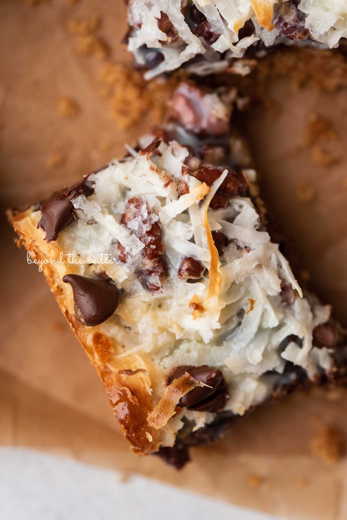 Magic cookie bars on brown parchment paper | © Beyond the Butter®