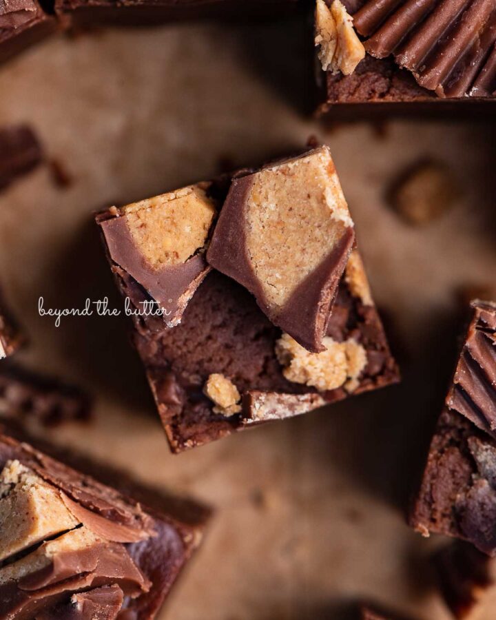 Sliced homemade chocolate peanut butter fudge on brown parchment paper.