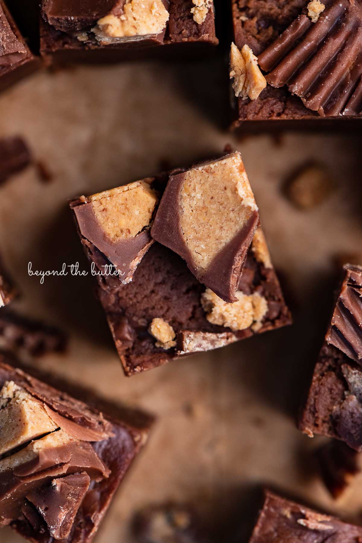 Sliced homemade chocolate peanut butter fudge on brown parchment paper.