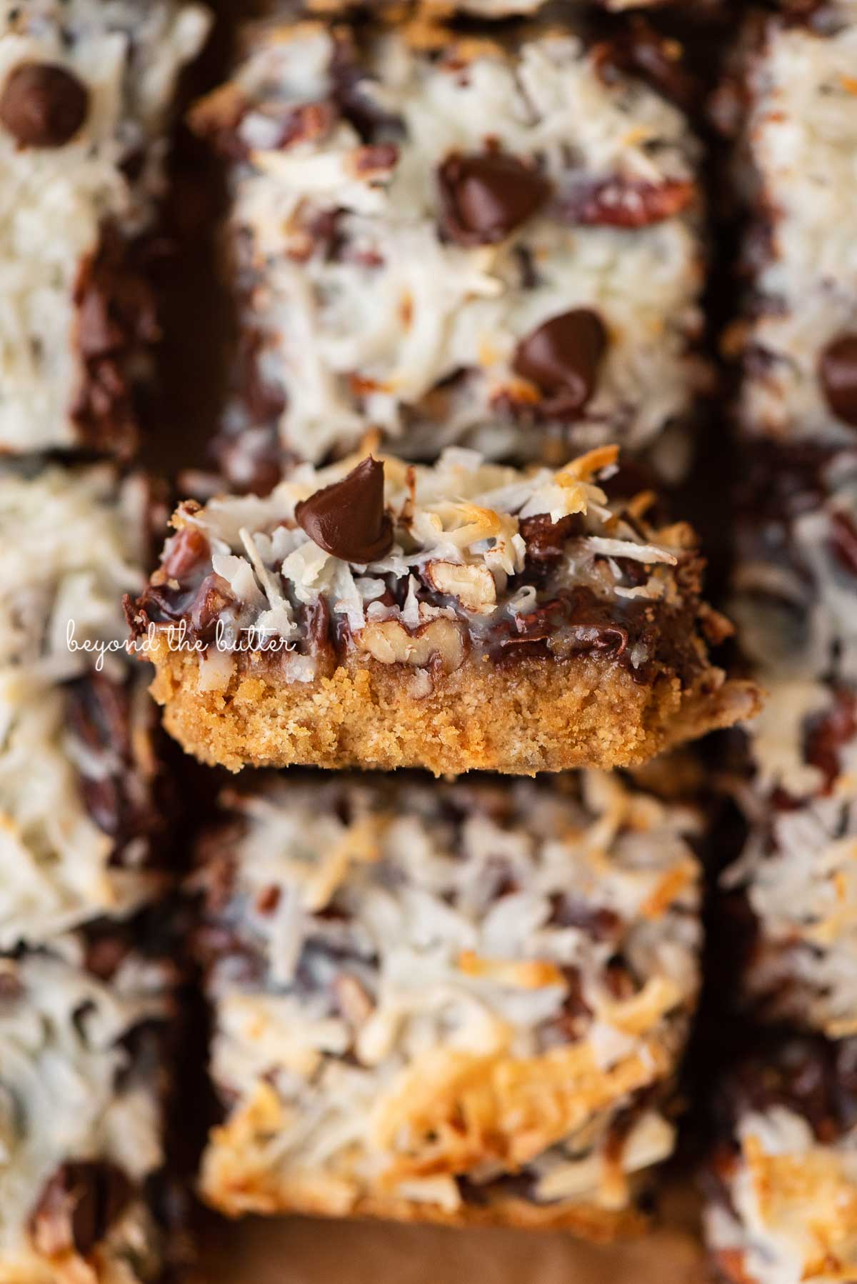 Sliced 7 layer magic cookie bars with center bar on its side | © Beyond the Butter®