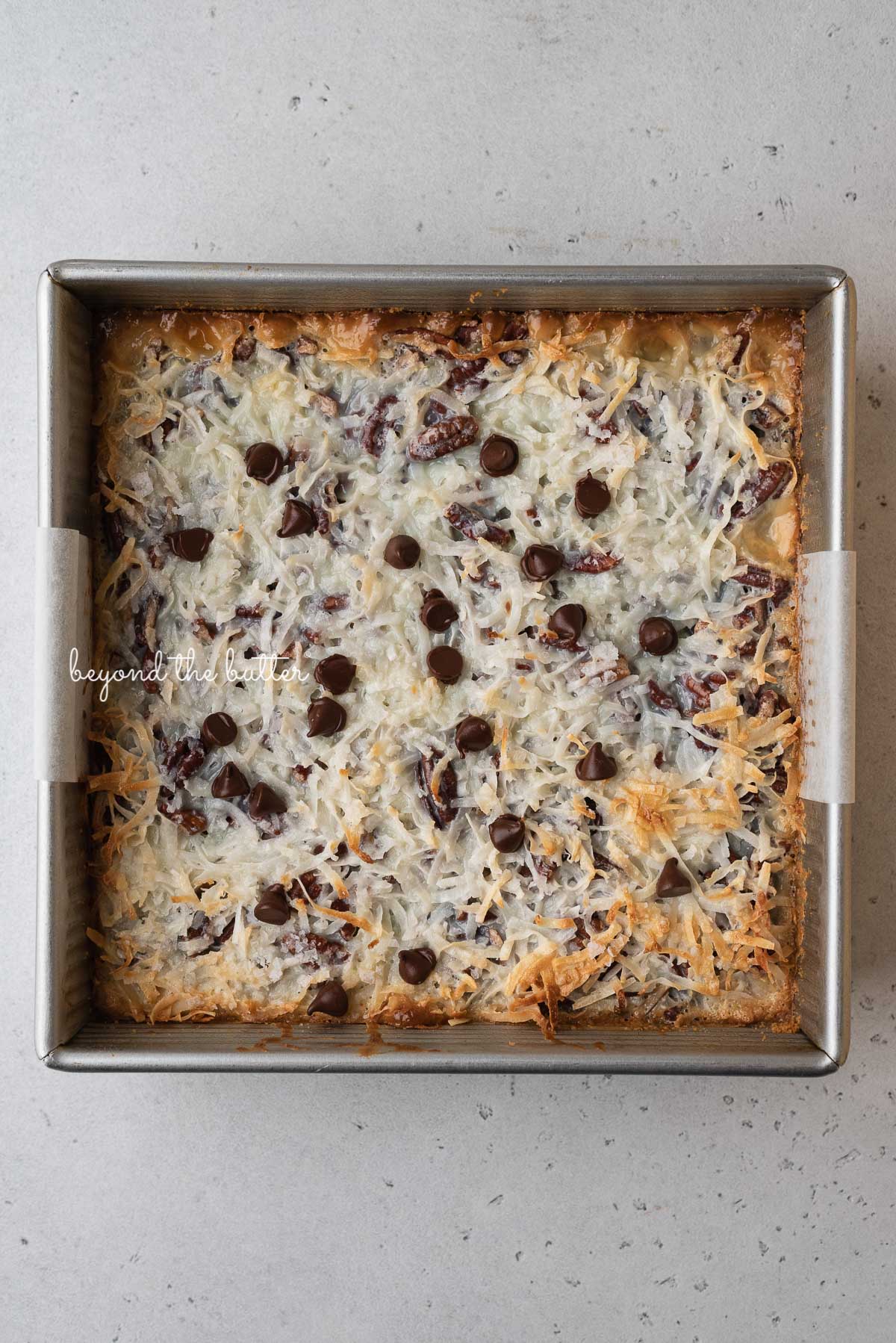 Just baked 7 layer magic cookie bars in 8 inch baking pan | © Beyond the Butter®