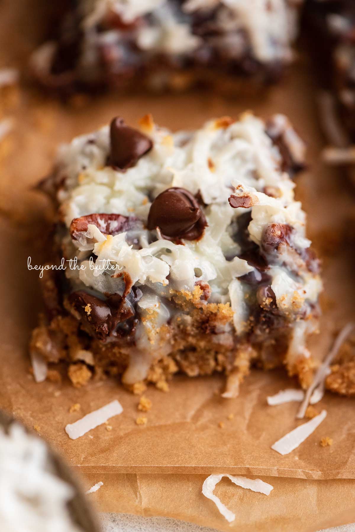 Sliced magic cookie bars on brown parchment paper | © Beyond the Butter®
