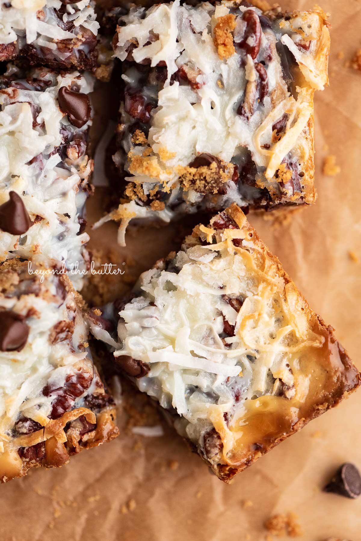 Sliced magic cookie bars on brown parchment paper | © Beyond the Butter®