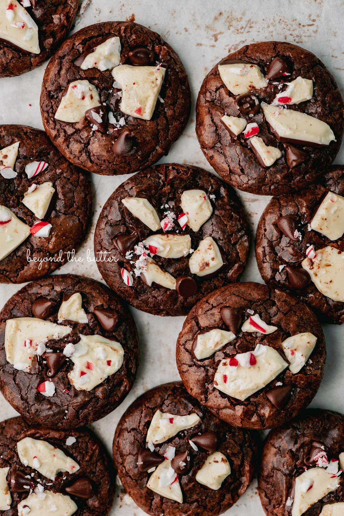 Just baked peppermint bark brownie crinkle cookies on a parchment paper lined baking sheet | © Beyond the Buter®