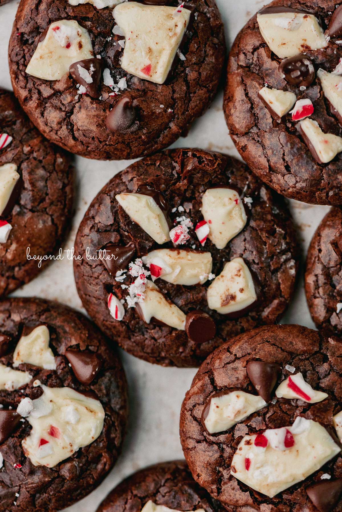 Baked peppermint bark brownie cookies on a parchment paper lined baking sheet | © Beyond the Buter®
