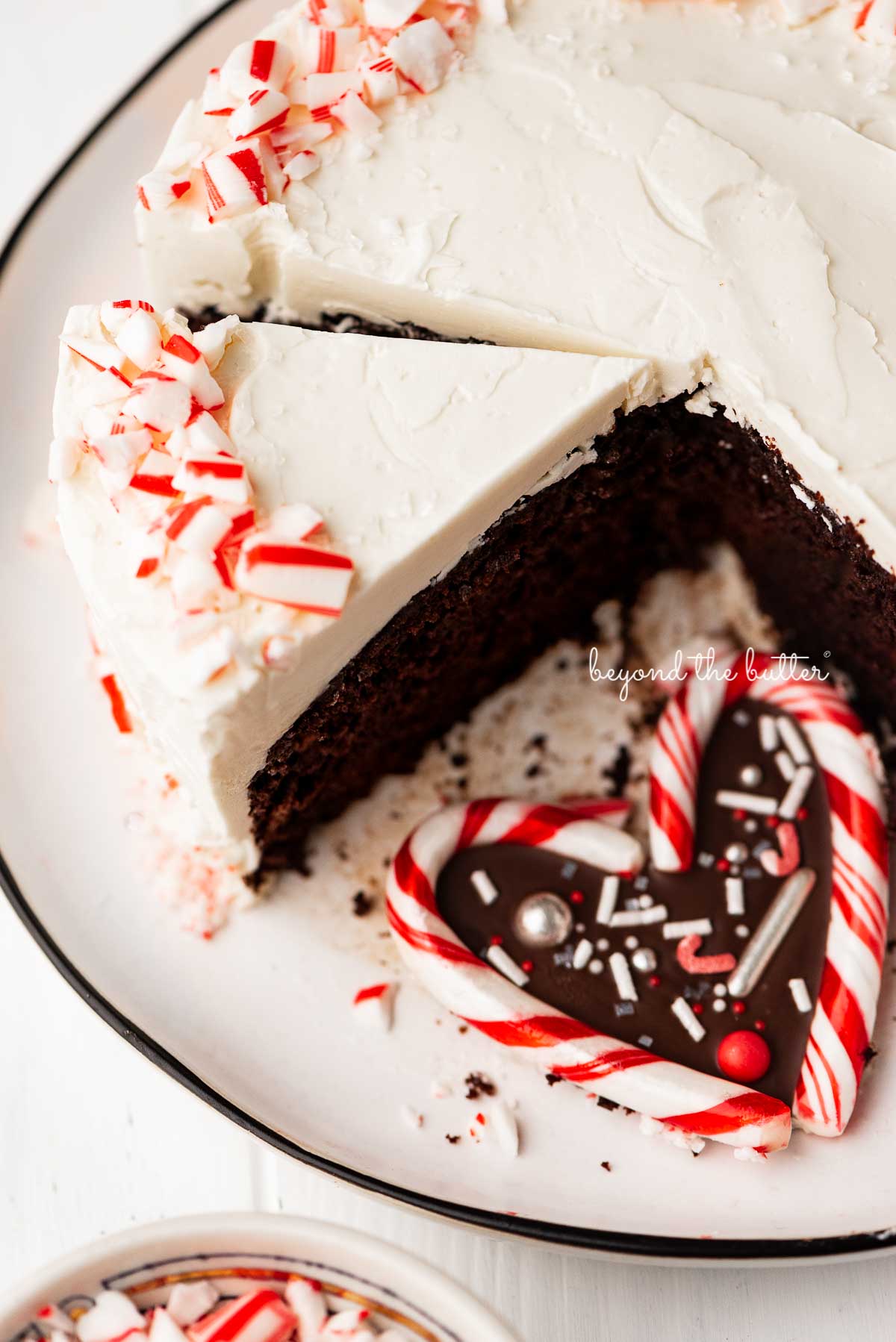 Single layer chocolate peppermint cake sliced with candy cane heart placed on the dessert plate | © Beyond the Butter®