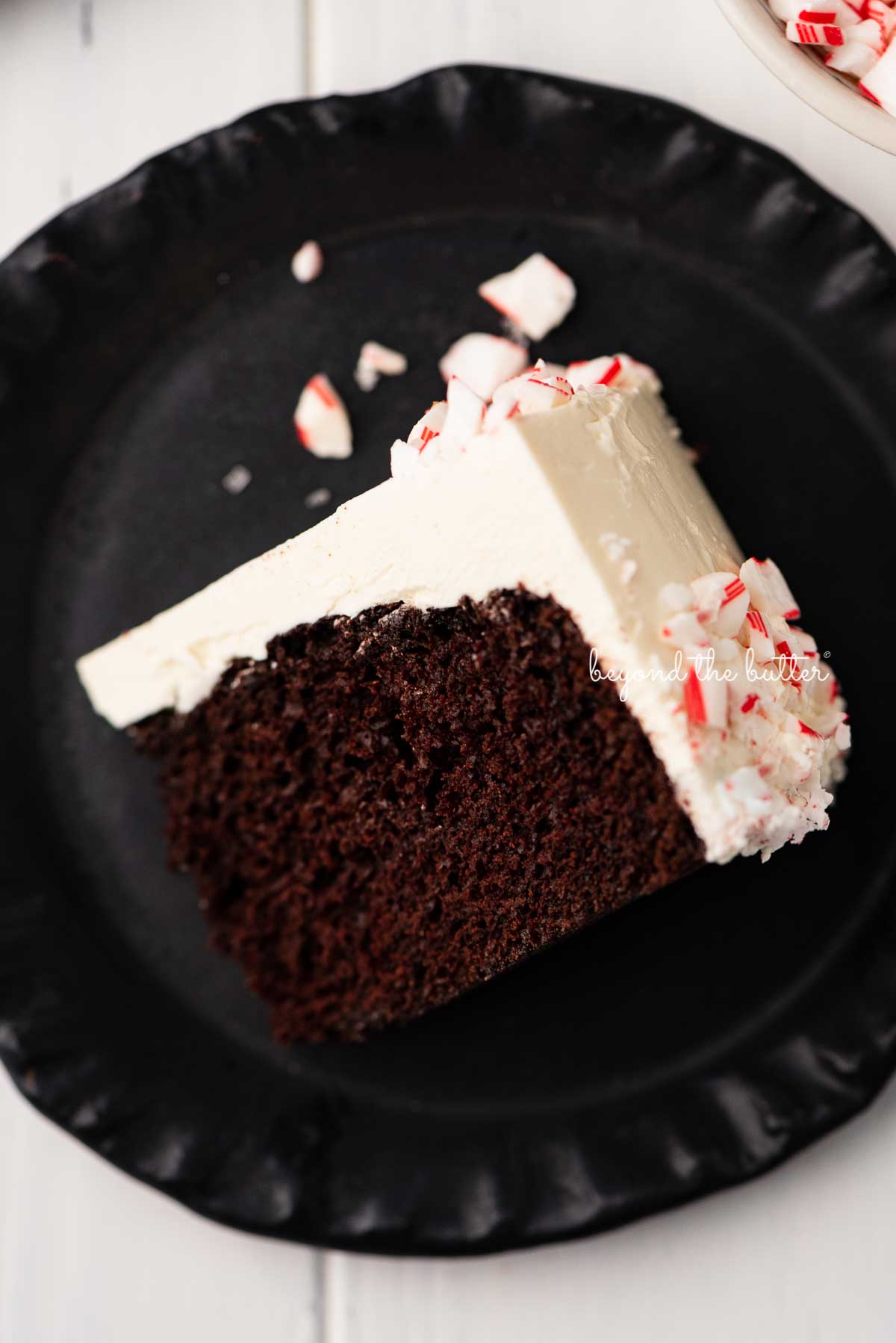 Slice of chocolate peppermint cake on a black ceramic dessert plate | © Beyond the Butter®