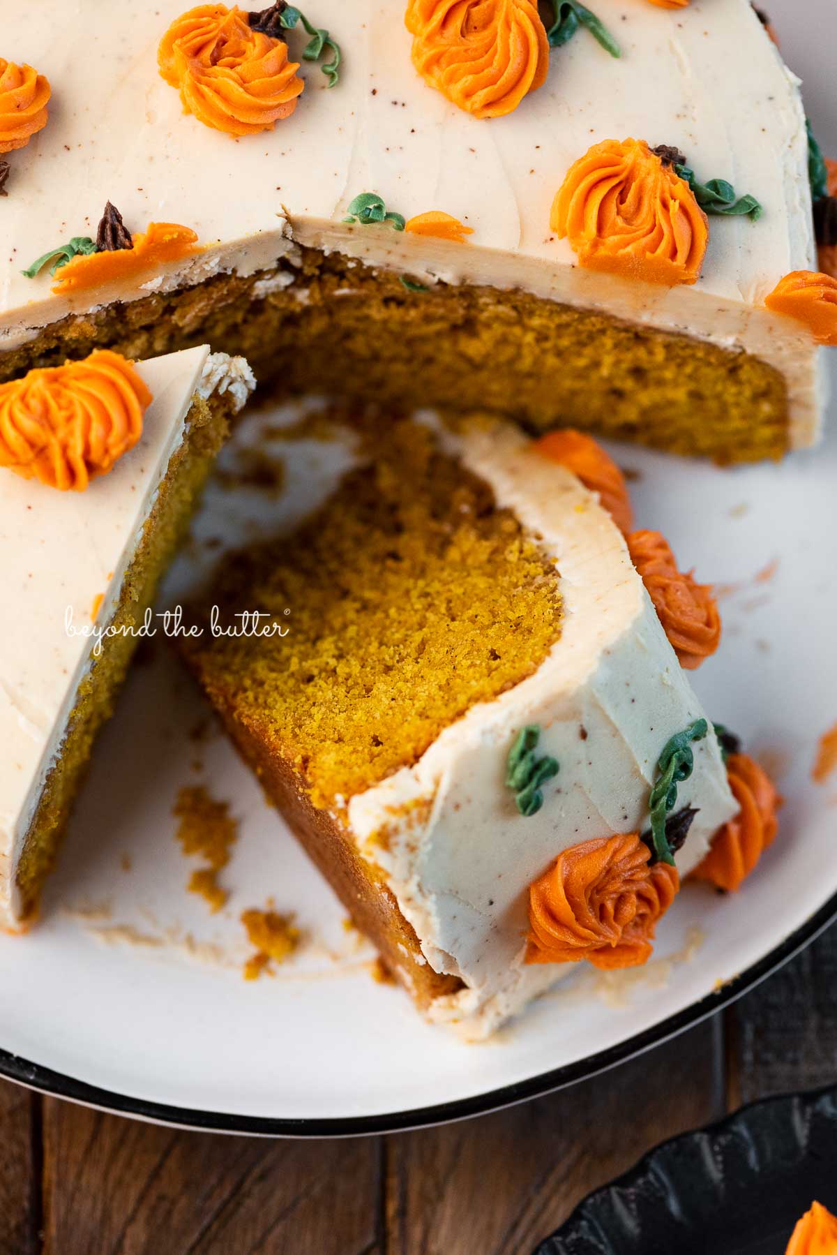 Slices of pumpkin spice cake with espresso buttercream frosting on a black and white dessert plate | © Beyond the Butter®