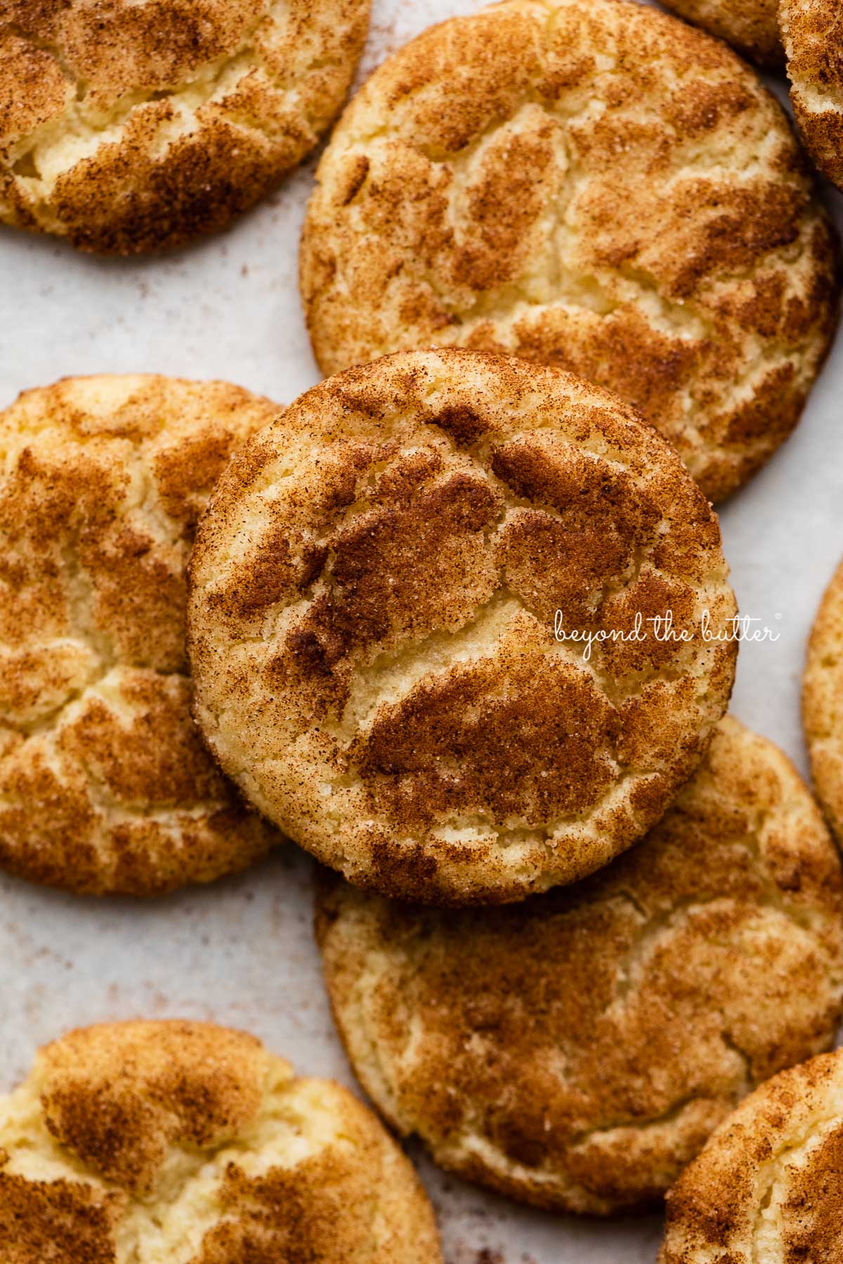 Snickerdoodle cookies on a parchment paper lined baking sheet | © Beyond the Butter®
