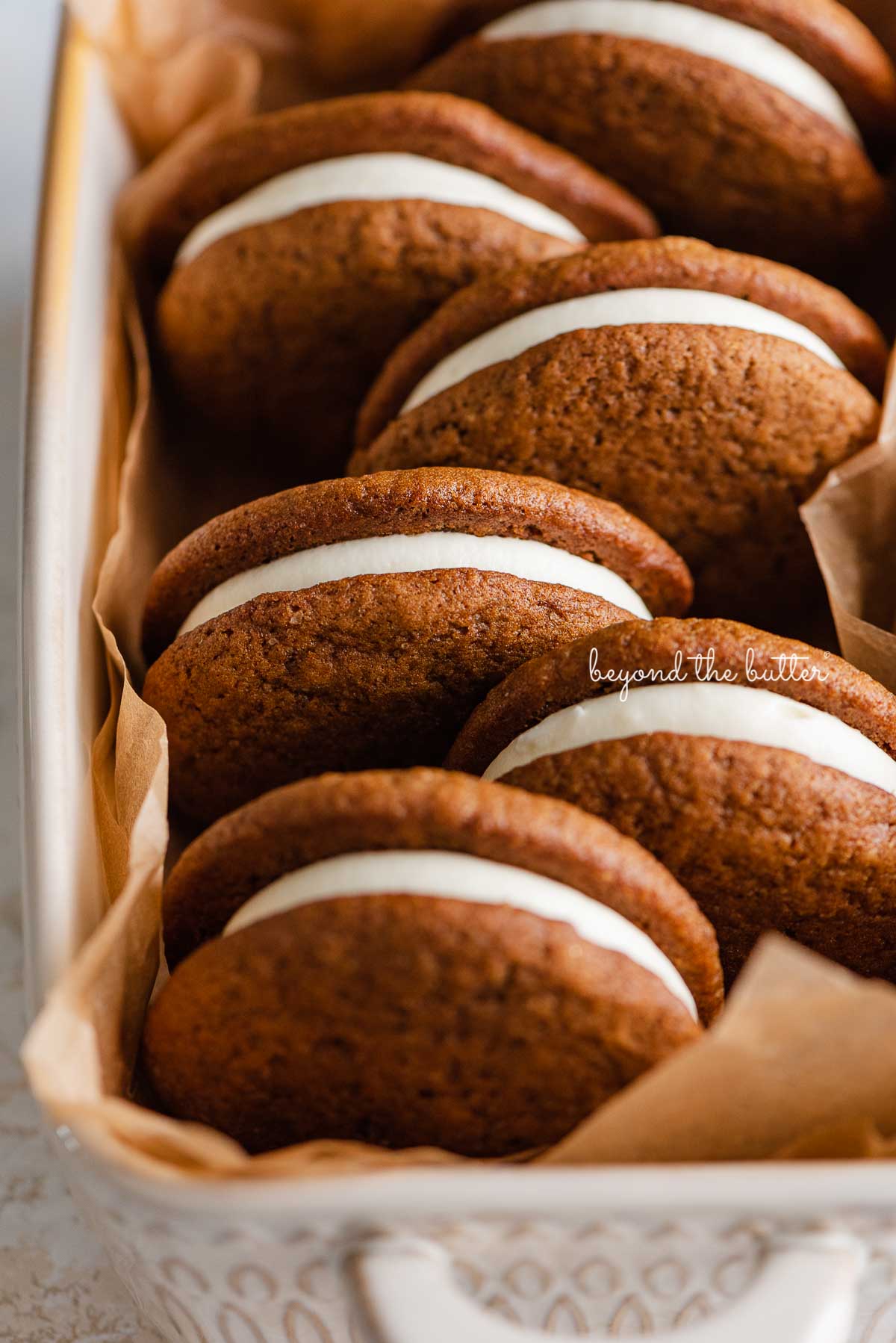 Natural parchment paper lined ceramic baking pan with homemade gingerbread whoopie pies | © Beyond the Butter®